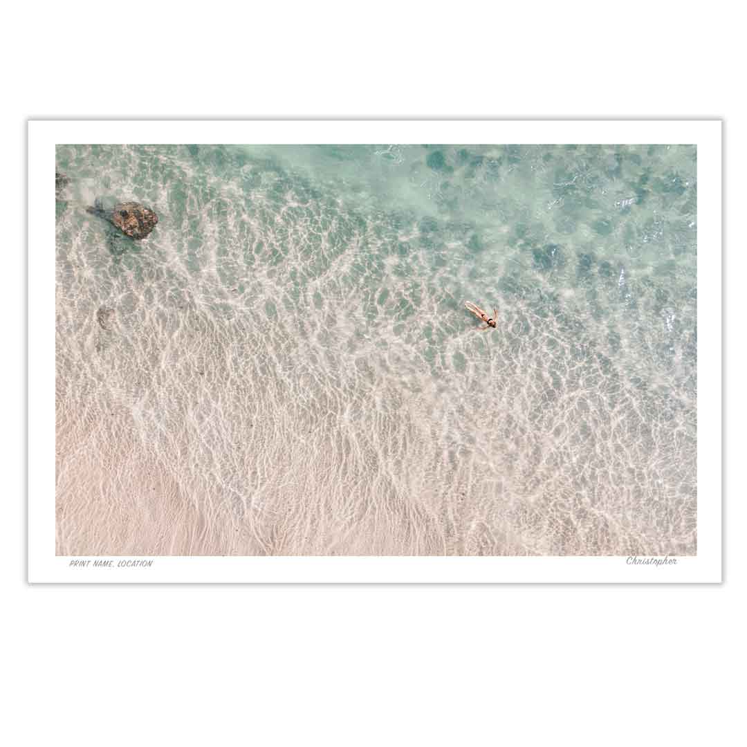 Top-down view of a beach with clear water and a person in a kayak.