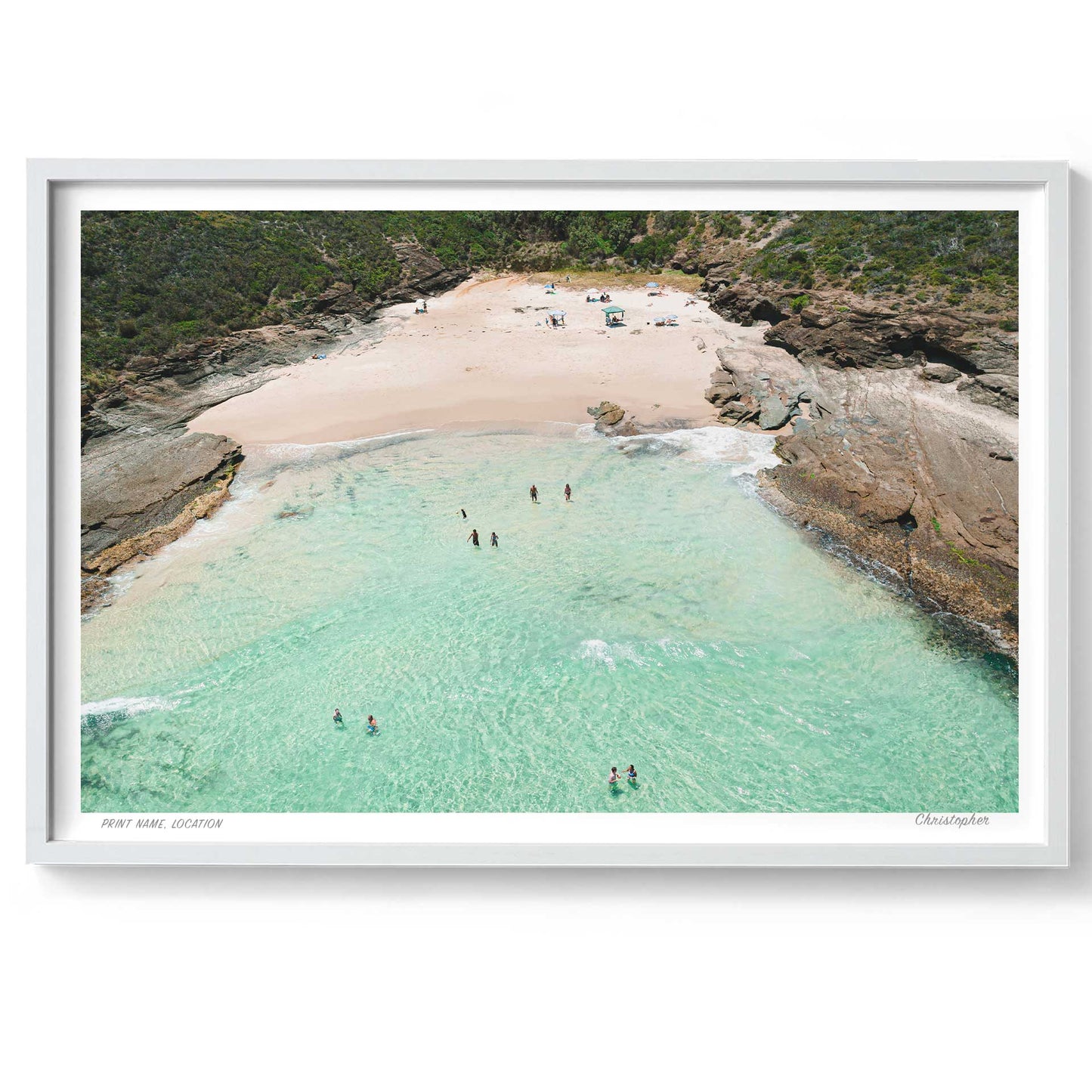 Framed artwork of a beach scene with clear turquoise water and sandy shore.