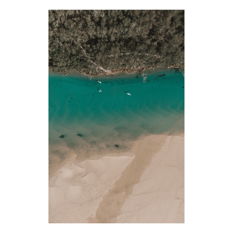 A peaceful aerial view of Corindi River flowing into Red Rock, NSW, with turquoise waters, golden sands, and boats drifting across the river.