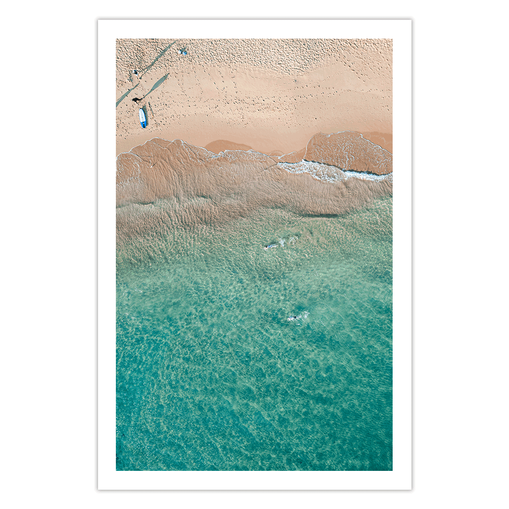 Aerial view of a lone swimmer gliding through the clear turquoise waters of Avoca Beach, NSW, with golden sand meeting the gentle ocean waves.