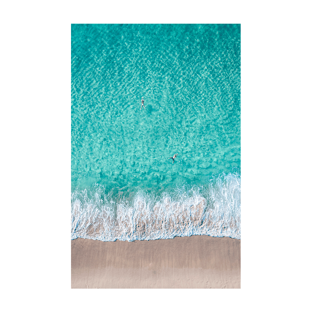 A stunning aerial view of Bronte Beach, Sydney, featuring swimmers floating in turquoise waters as waves meet the sandy shore.