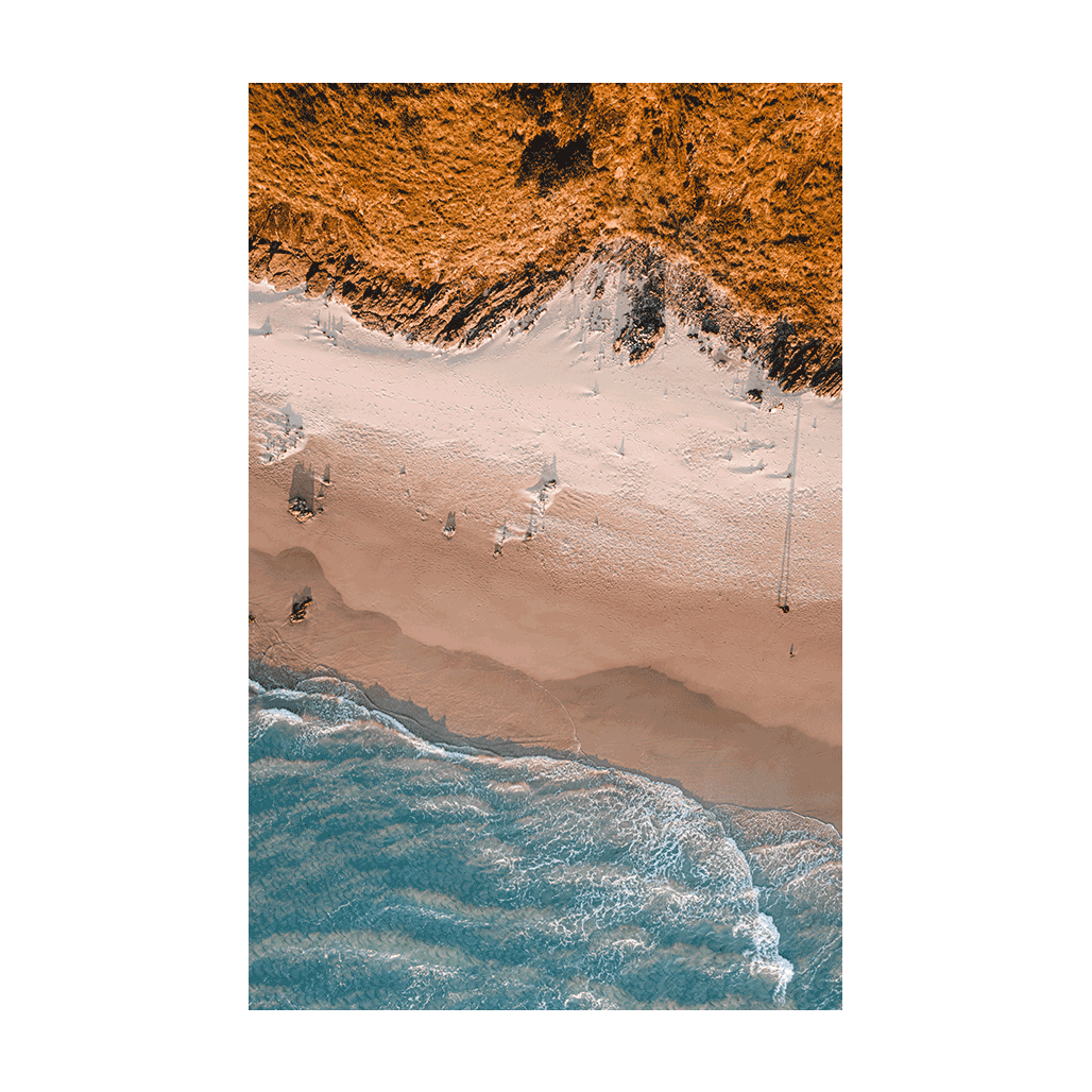 A striking aerial print of Wategos Beach, Byron Bay, NSW, showcasing golden dunes, rugged cliffs, and the deep blue ocean in a stunning coastal composition.