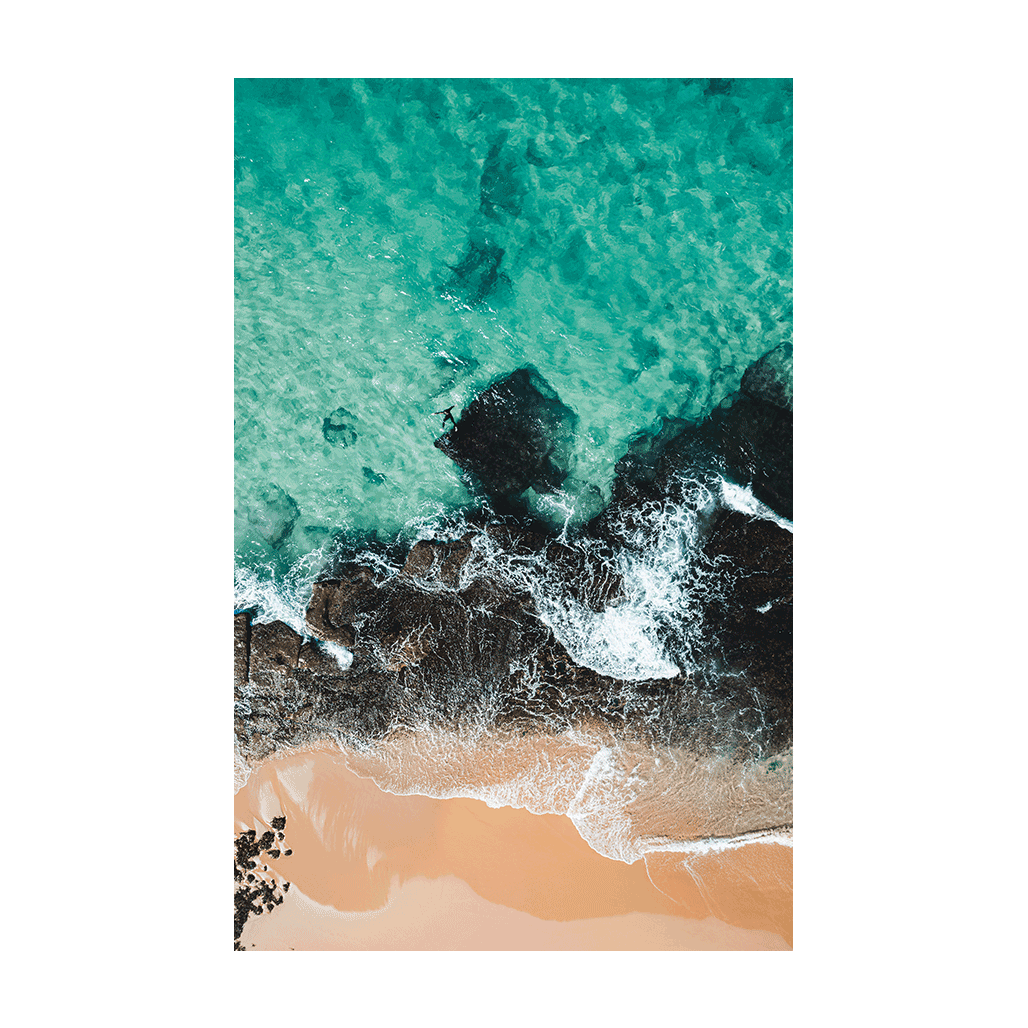 Aerial view of Forresters Beach, NSW, showing turquoise ocean waves crashing against dark coastal rocks and golden sand.