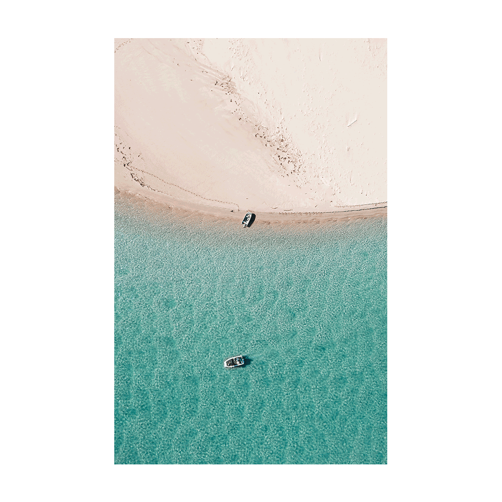 A stunning aerial view of Nambucca Beach, NSW, featuring two boats floating on turquoise waters near untouched sand dunes.