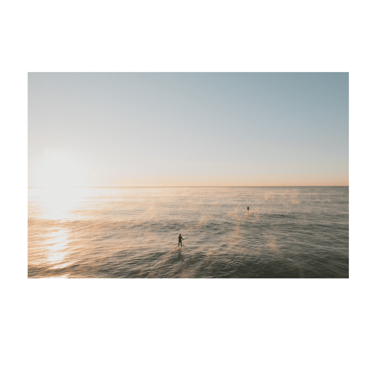 A peaceful ocean scene at Terrigal Beach, NSW, where mist rises from the water as paddleboarders move across the calm sea at sunrise.