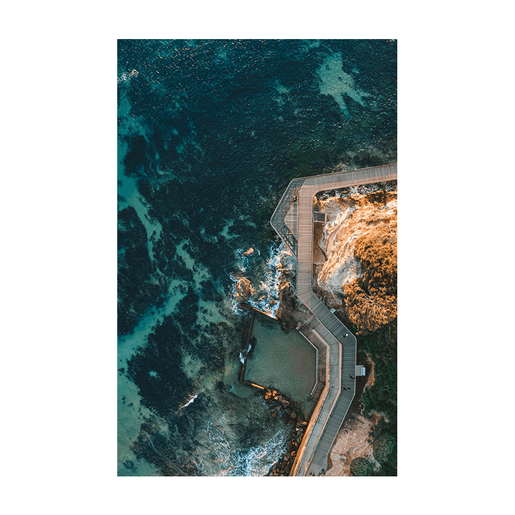 Aerial view of Terrigal’s boardwalk and ocean pool, curving along the rugged coastline with deep blue ocean waters surrounding it.