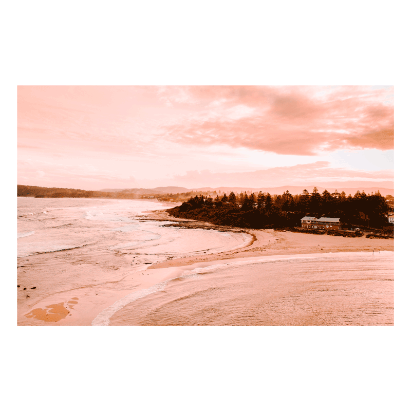Aerial view of Toowoon Bay Beach bathed in soft pink hues, capturing a serene coastal landscape at sunset. The warm tones highlight the shoreline, waves, and surrounding scenery, making it a perfect addition to any beach-inspired space.
