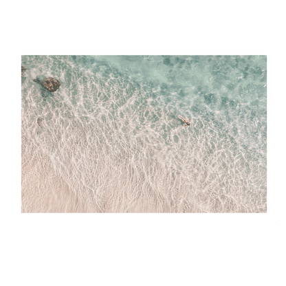 Top-down view of a beach with clear water and a person swimming.