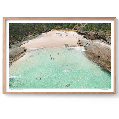 Framed photograph of a beach with clear turquoise water and sandy shore.