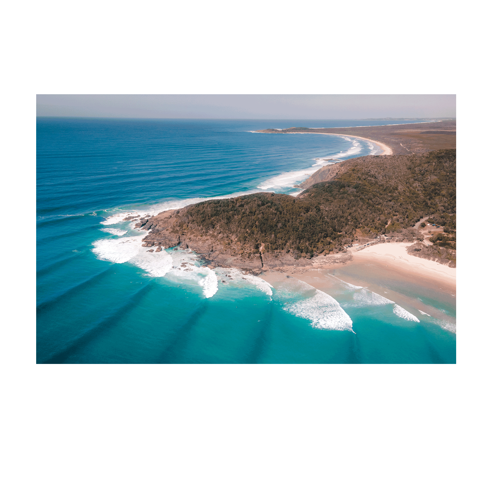 Aerial view of Big Hill Beach at Crescent Head, NSW, showcasing turquoise waters, rolling waves, and a rugged coastal landscape.
