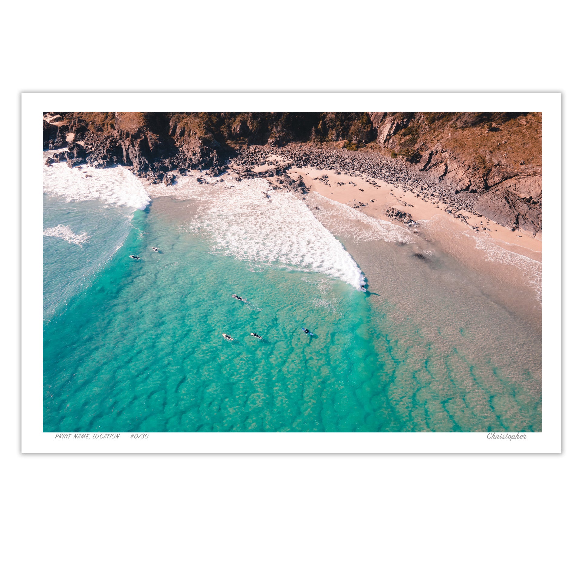 A stunning aerial view of Racecourse, Crescent Head, NSW, featuring surfers paddling in turquoise waves near a rugged coastline.

