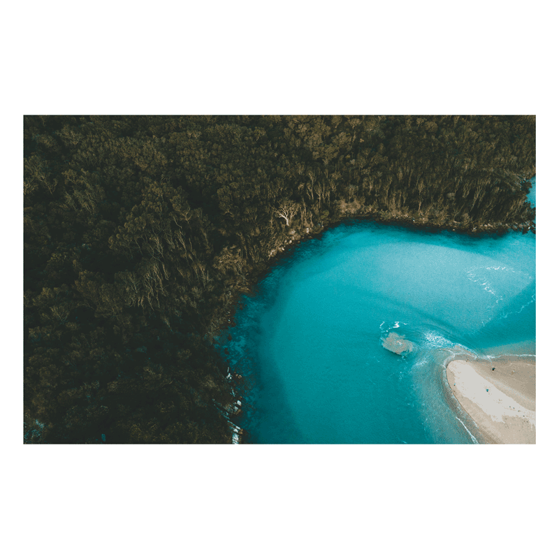 A breathtaking aerial view of Hat Head, NSW, showcasing the contrast between lush forest and vibrant turquoise coastal waters.