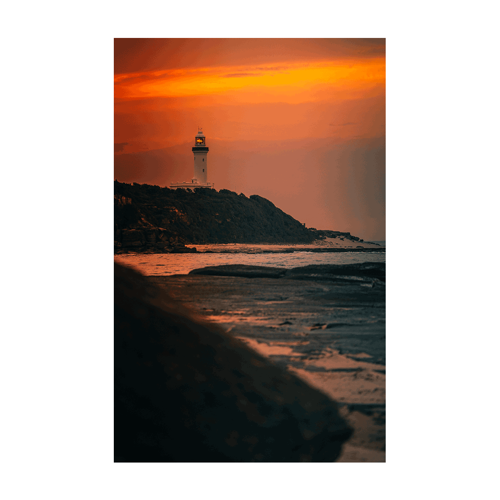 A dramatic coastal sunset at Norah Head, NSW, with a glowing magenta sky over the lighthouse and rugged coastline.