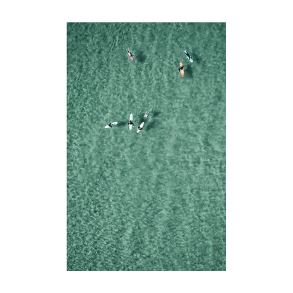 Aerial view of surfers and paddleboarders floating together in the clear turquoise waters of North Avoca Beach, NSW, enjoying a peaceful ocean moment.