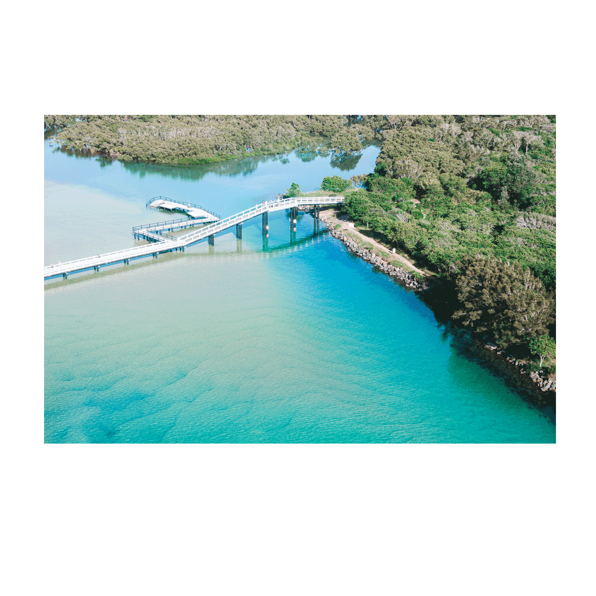 A stunning aerial print of South West Rocks, NSW, featuring a charming wooden bridge crossing over vibrant turquoise waters and lush greenery.