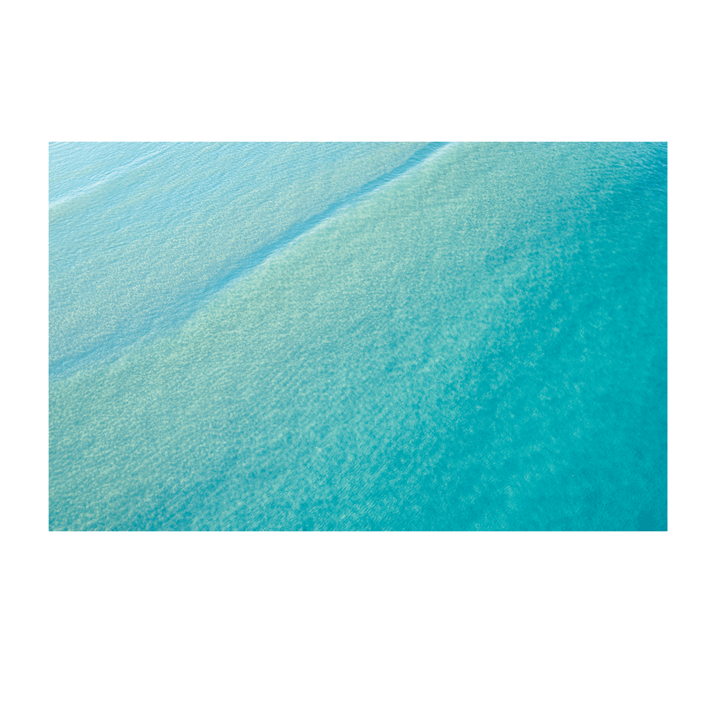 Aerial view of crystal-clear turquoise waters at Terrigal Beach, NSW, showcasing gentle ripples and shifting ocean hues.
